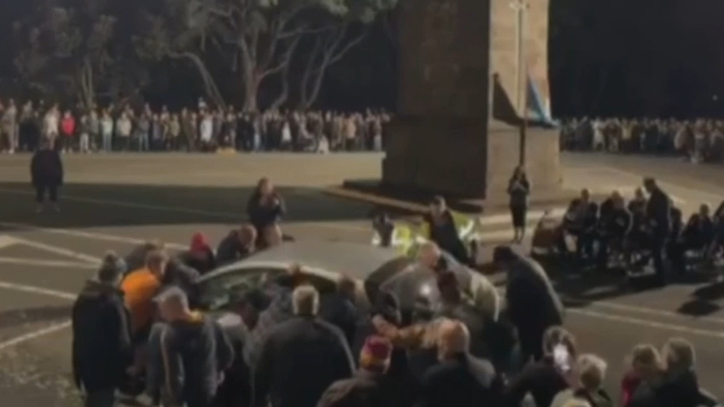 Crowd lifts car out of the way of Anzac ceremony